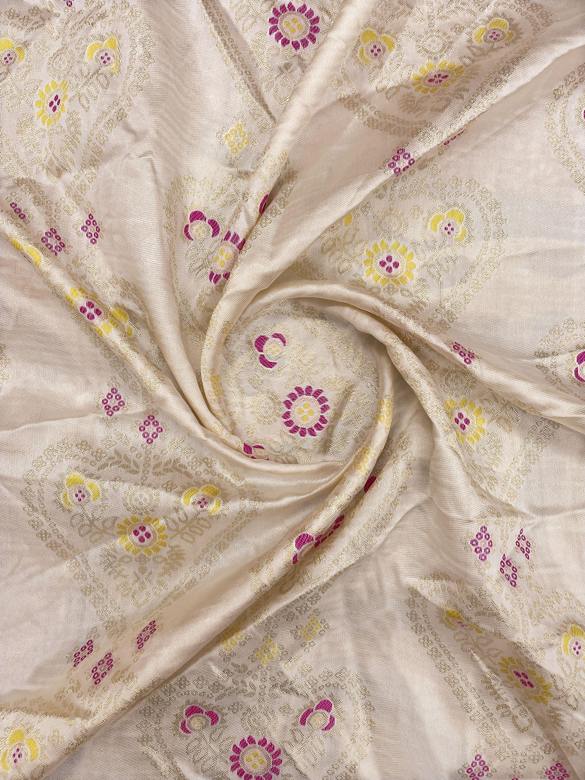 White raw silk fabric with intricate pink and golden floral embroidery